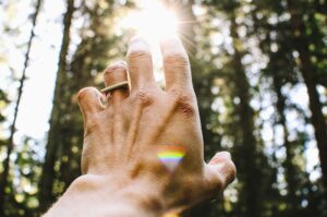 Man's hand reaching for the light in a forest